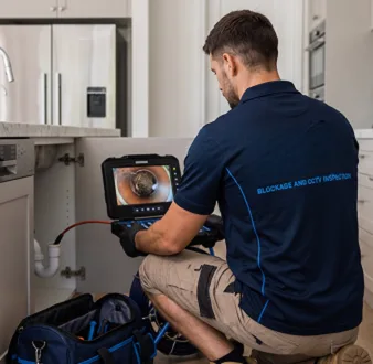 Plumber clearing a blocked toilet in a Yagoona bathroom